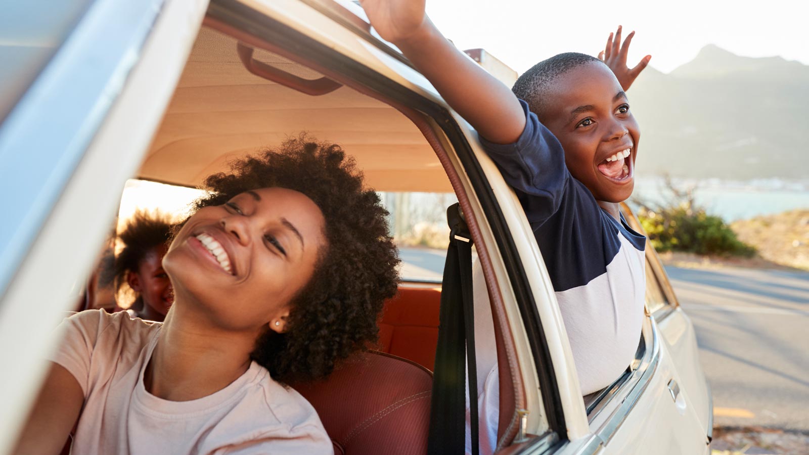 a mother and son in a car with their heads out the window